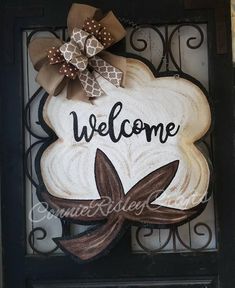 a welcome sign hanging on the side of a door with a brown bow and polka dot ribbon