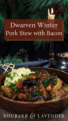 a wooden bowl filled with food next to a lit candle and pine tree in the background