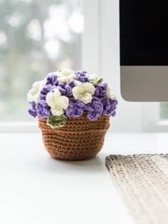 a crocheted flower pot sitting on top of a white table next to a computer