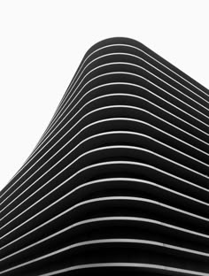 a black and white photo of a building with vertical lines on the side, against a cloudy sky