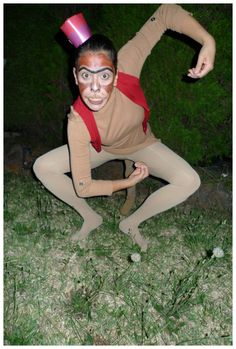 a woman with makeup on her face is posing in the grass wearing a hat and leggings