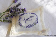 lavender embroidered onto a pillow with the word lavender on it next to some lavender flowers