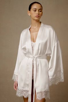 Got you covered.The ANNABETH Lace Trim Bridal Robe in White features a V neckline and wrap design, exuding elegance and sophistication. Its long sleeves and drop shoulder silhouette offer comfort and grace, while the satin fabrication adds a luxurious touch. Delicate lace trims on the sleeves and hemline add a romantic flair, complemented by the satin sash for a cinched waist. Unlined for lightweight comfort, this robe is perfect for getting ready on your special day. This style is a Pearl White Bridal Robes Getting Ready, Rembo Styling, Silky Robe, Bridal Robe, Wedding Robe, Satin Sash, Lace Trims, Wedding Lingerie, Bridal Robes