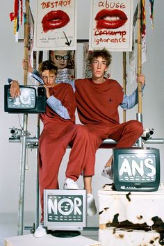 two people sitting on top of televisions with signs above them that say no more