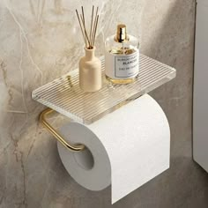 a white toilet paper holder next to a roll of toilet paper and a bottle of perfume