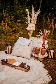 an outdoor picnic with bread, coffee and marshmallows on a blanket in the grass