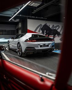 a white sports car driving down a street next to a horse painted on the wall