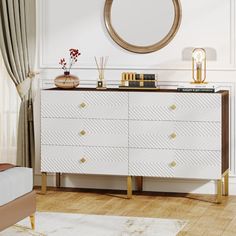 a white dresser with gold accents and a round mirror