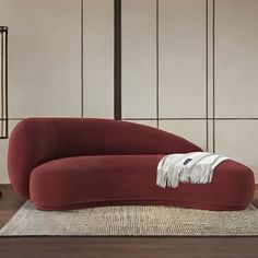 a large red couch sitting on top of a wooden floor next to a white rug