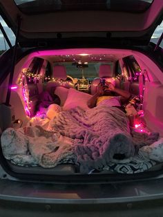 the trunk of a car is filled with blankets and lights, while two people lay in bed