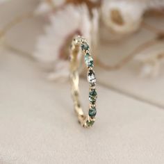 a gold ring with green and white stones