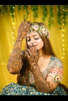 a woman with henna on her hands and flowers in her hair is posing for the camera