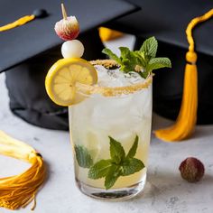 a drink with lemon and mint garnish in a glass next to a tassel