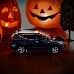 a toy car is parked in front of two carved jack - o'- lanterns