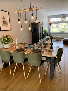 a dining room table with green chairs and lights hanging from the ceiling