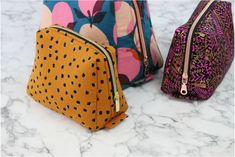 three different colored bags sitting on top of a marble countertop next to each other