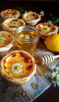 there are many pies with flowers on them and honey in the jar next to it