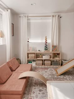 a living room filled with furniture and a window covered in white draping next to a wooden shelf