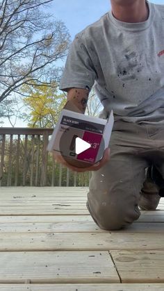 a man kneeling on a deck holding a box