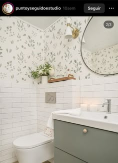 a white toilet sitting next to a sink in a bathroom under a mirror and light