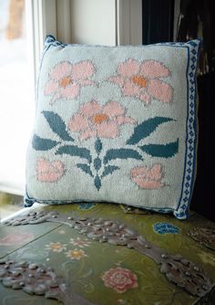 a decorative pillow sitting on top of a green chair next to a window sill