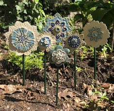 four decorative garden stakers sitting in the dirt