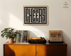 a record player sitting on top of a wooden cabinet next to a wall mounted poster