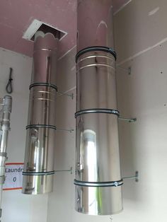 two stainless steel tanks mounted to the side of a wall in a room with pink walls