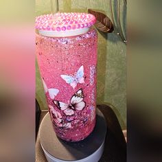 a pink cup with butterflies painted on it