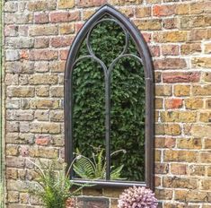 a window that is next to a brick wall with plants in the windowsills