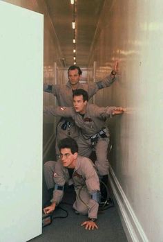 three men are standing in the hallway with their arms out and one man is holding his hand up