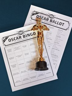 an oscar award is placed on top of a sheet of paper next to a golden statue