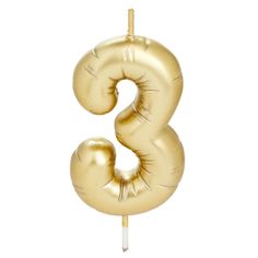 the number 3 is made out of gold foil and sits on top of a stick