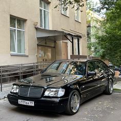 a black mercedes parked in front of a building