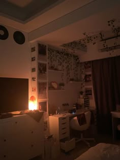 a dimly lit bedroom with the tv on and desk in front of it's screen