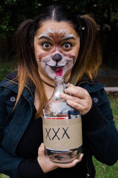 a woman with her face painted like a dog holding a bottle in front of her face