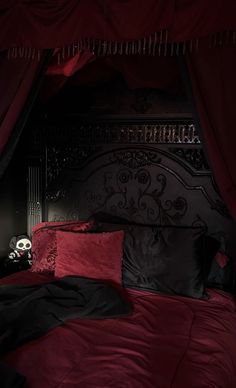 a bed with red sheets and black pillows in a room that looks like it has been set up for halloween