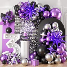 purple and black balloons are on display in front of a large number 5 balloon arch