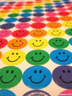 colorful smiley face stickers sitting on top of a rainbow colored tablecloth with circles