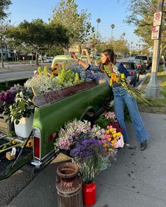 a woman standing next to a truck filled with flowers