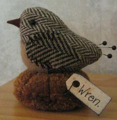 a small stuffed bird sitting on top of a wooden table next to a name tag