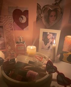 a table topped with pictures and candles next to a heart shaped candle holder on top of a table