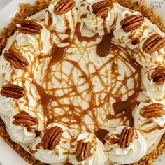 a pie with pecans and whipped cream on top is sitting on a white plate