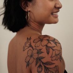 a woman with a tattoo on her shoulder and back is looking at the camera smiling