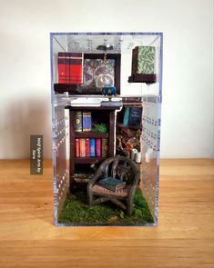 a miniature book shelf filled with books on top of a wooden table next to a chair