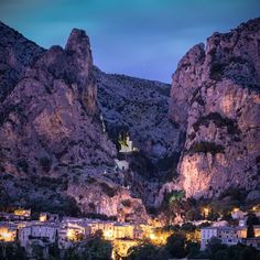 the mountains are lit up at night with lights on them and buildings in the foreground