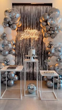 balloons and silver decorations are on display in front of a wall with the words happy new year