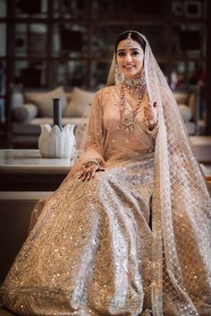 a woman sitting on top of a couch wearing a wedding dress and holding her finger up