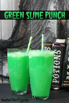 two glasses filled with green slime punch sitting on top of a table next to books