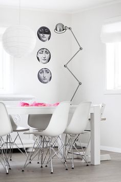 a dining room with white chairs and a table in front of a wall with pictures on it